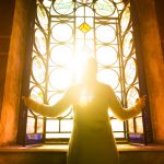 Religious woman in a church looking at the light shining through a stained glass window