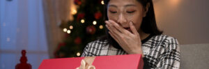 A woman opening a gif, covering her mouth in excitement