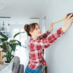Young woman using a measuring tape on the wall