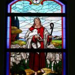 Stained glass window with Christ walking with sheep